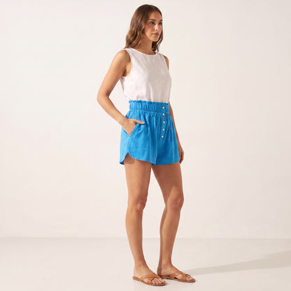 Posy Linen Shorts in bright blue, side view with a hand in the pocket
